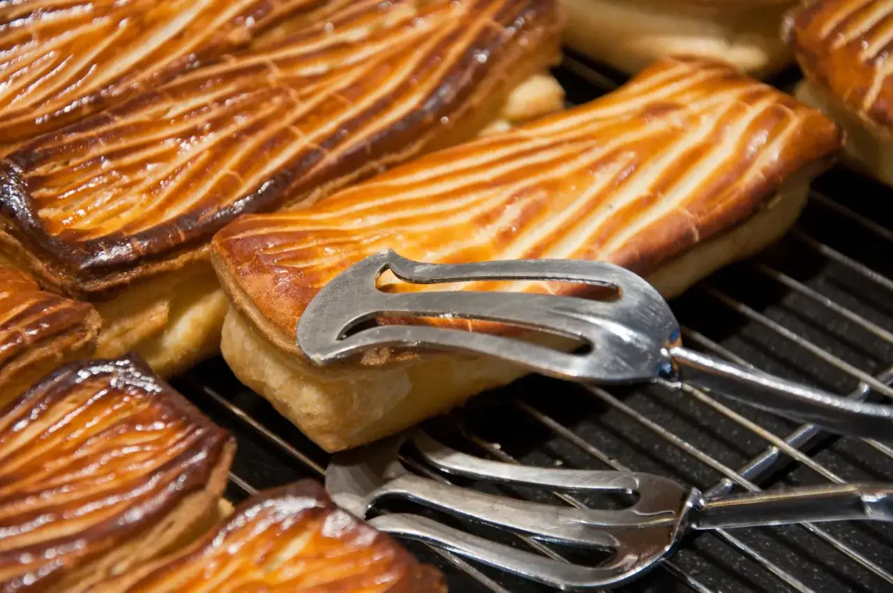 Des p&acirc;tisseries dor&eacute;es, une sp&eacute;cialit&eacute; de Nancy, attendent d'&ecirc;tre d&eacute;gust&eacute;es. Des pinces &agrave; p&acirc;tisserie sont pos&eacute;es sur les g&acirc;teaux.