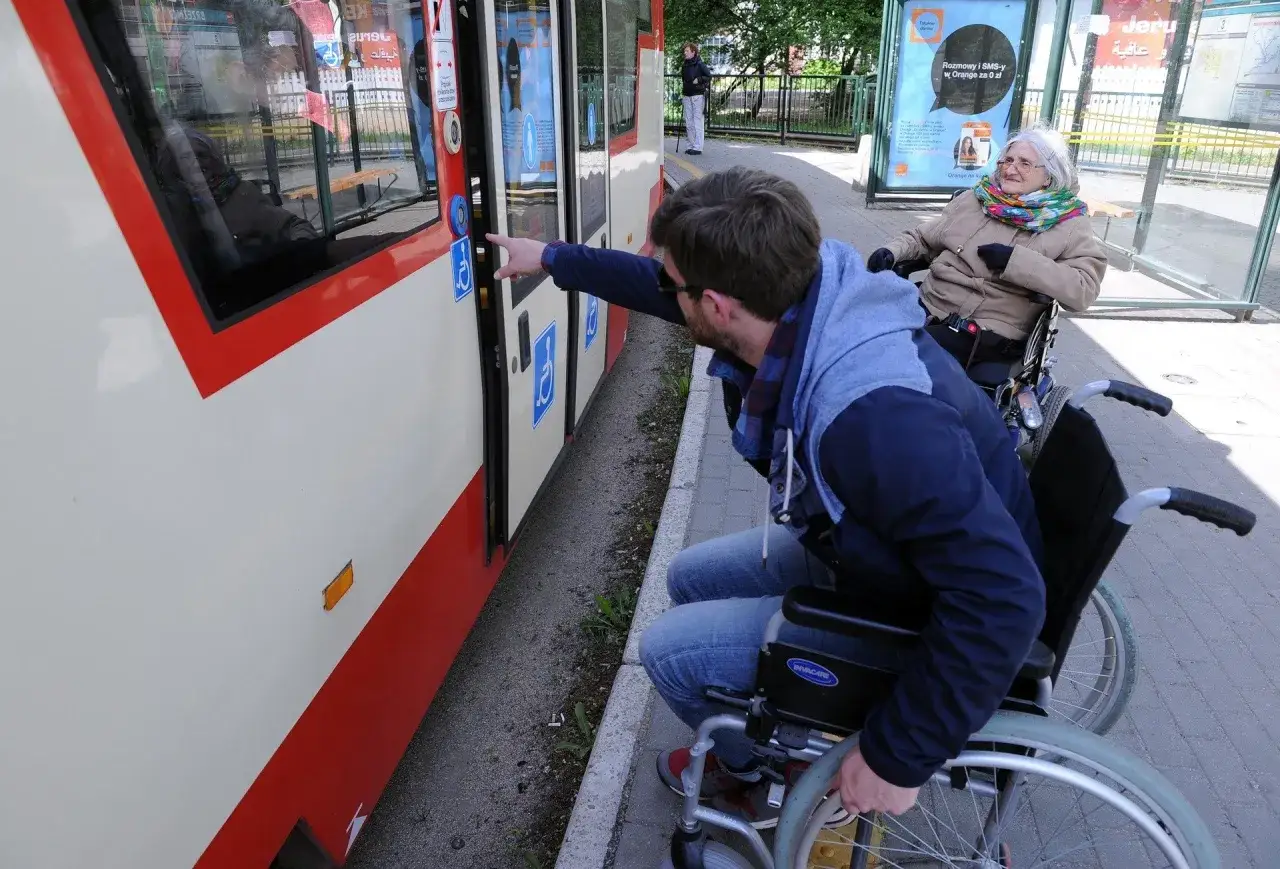 osoba na w&oacute;zku inwalidzkim na chodniku