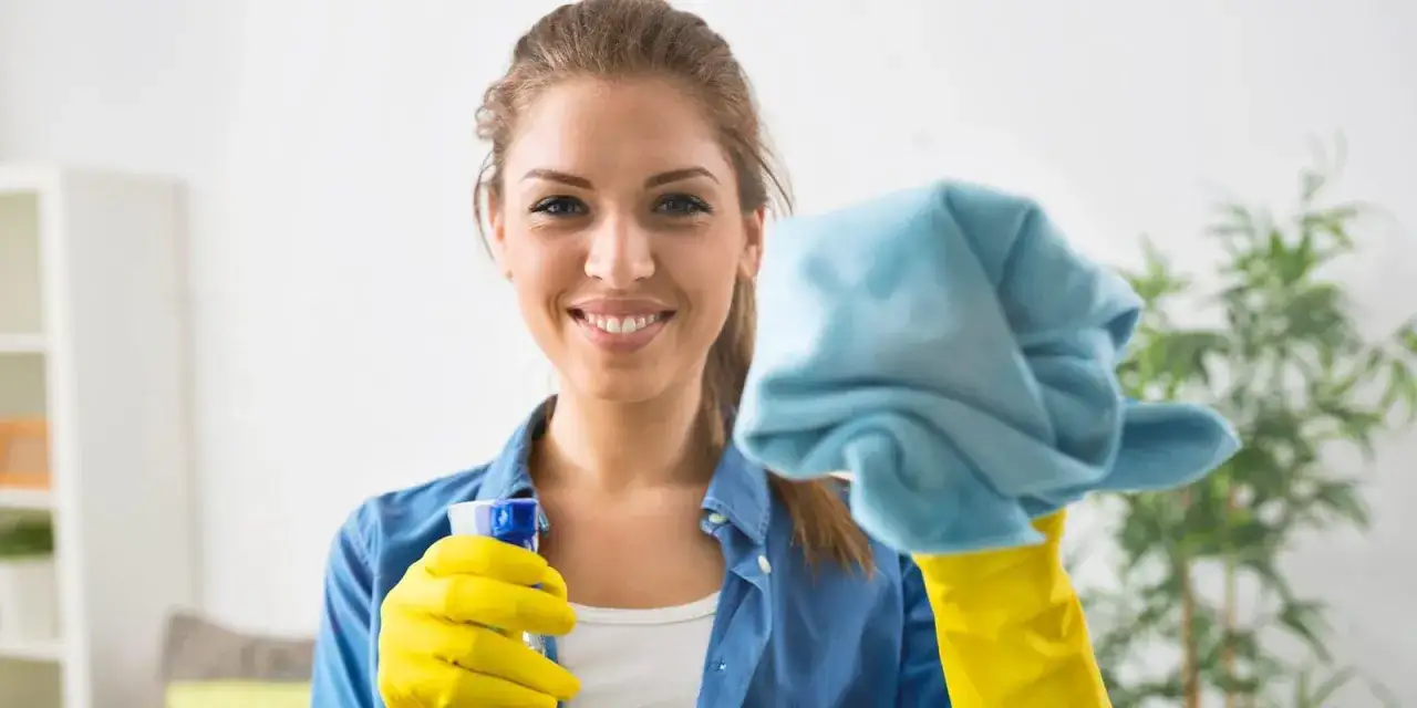 Donna sorridente con guanti gialli e panno blu, pronta a pulire le vetrate scorrevoli.
