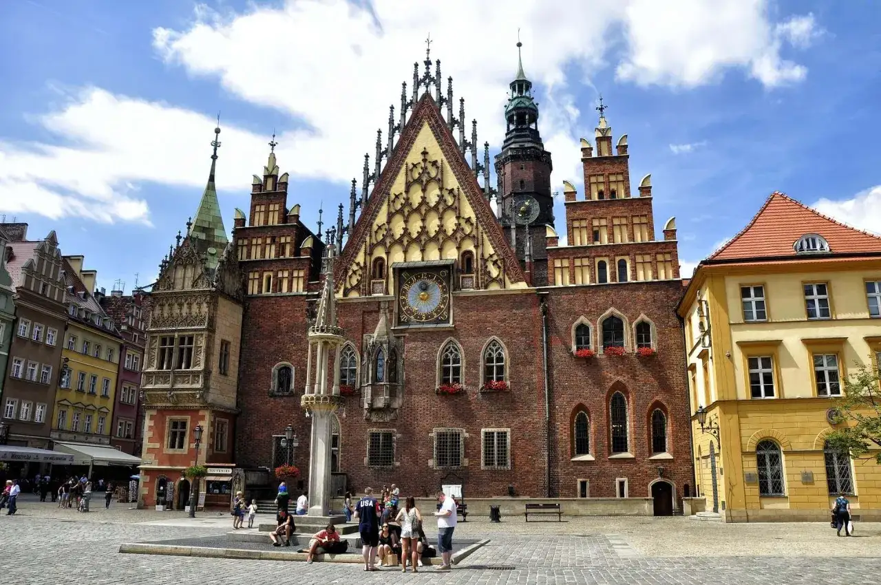 Majestatyczny ratusz we Wrocławiu, z bogato zdobioną fasadą i zegarem, góruje nad rynkiem.