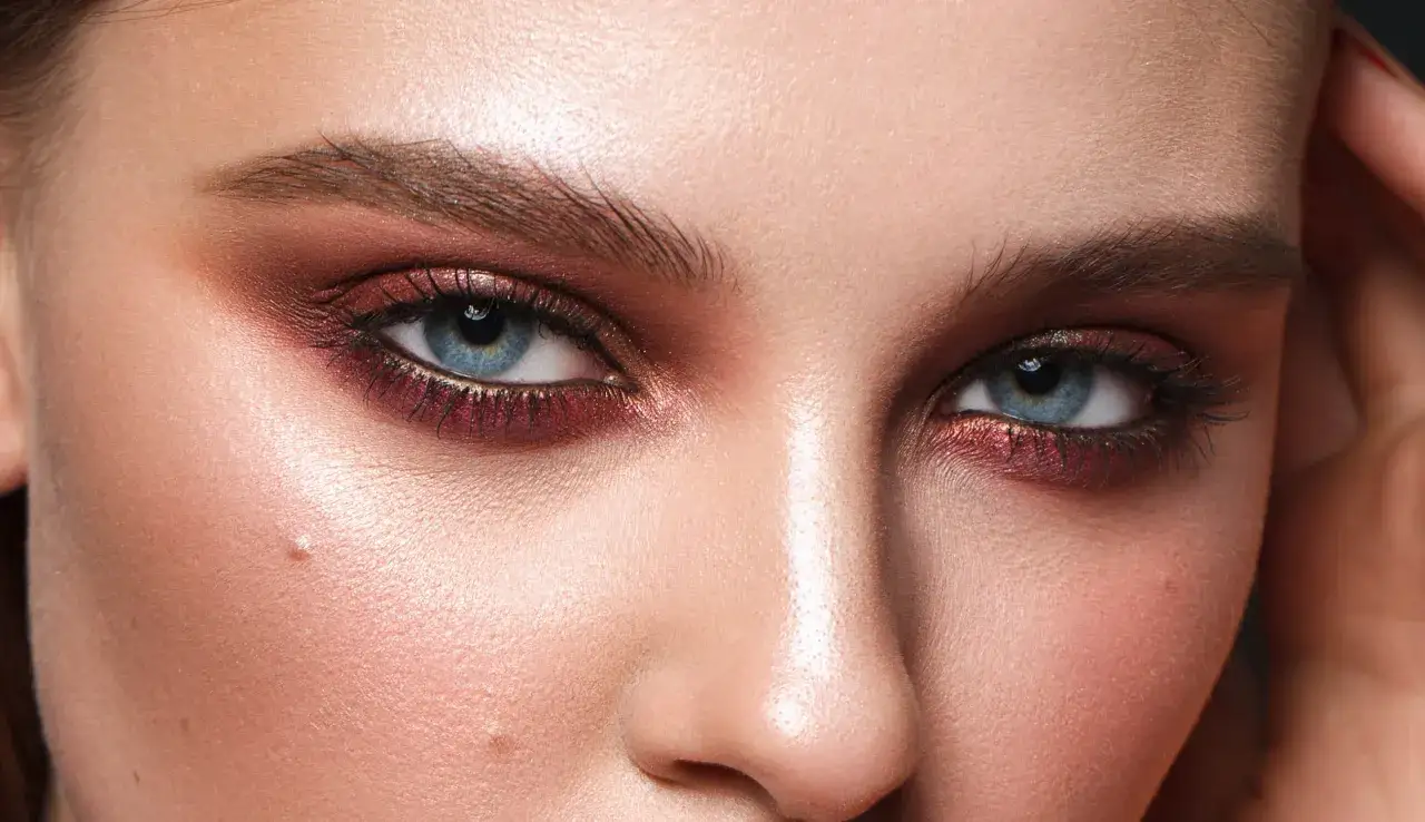 Ojos azules con sombras rojizas y delineador, creando combinaciones sombra delineador ojos impactantes.
