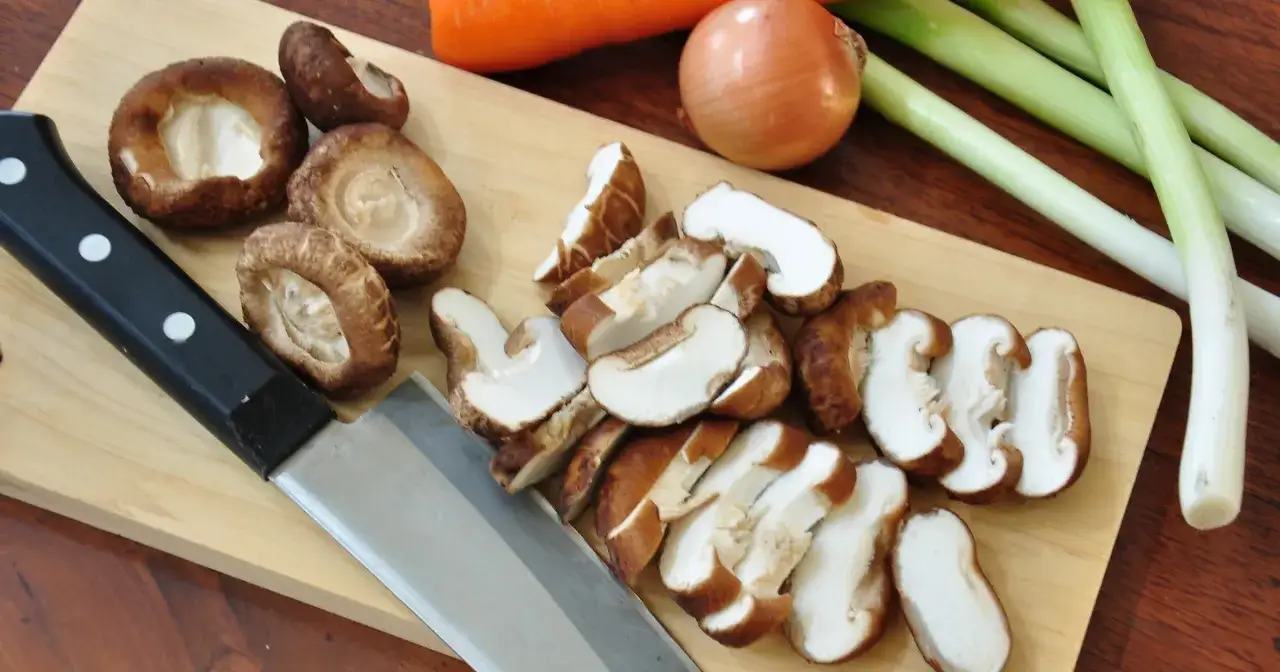 Pokrojone grzyby shiitake, cebula, marchewka i szczypiorek na desce. Grzyby wartości odżywcze są bogate w witaminy i minerały.