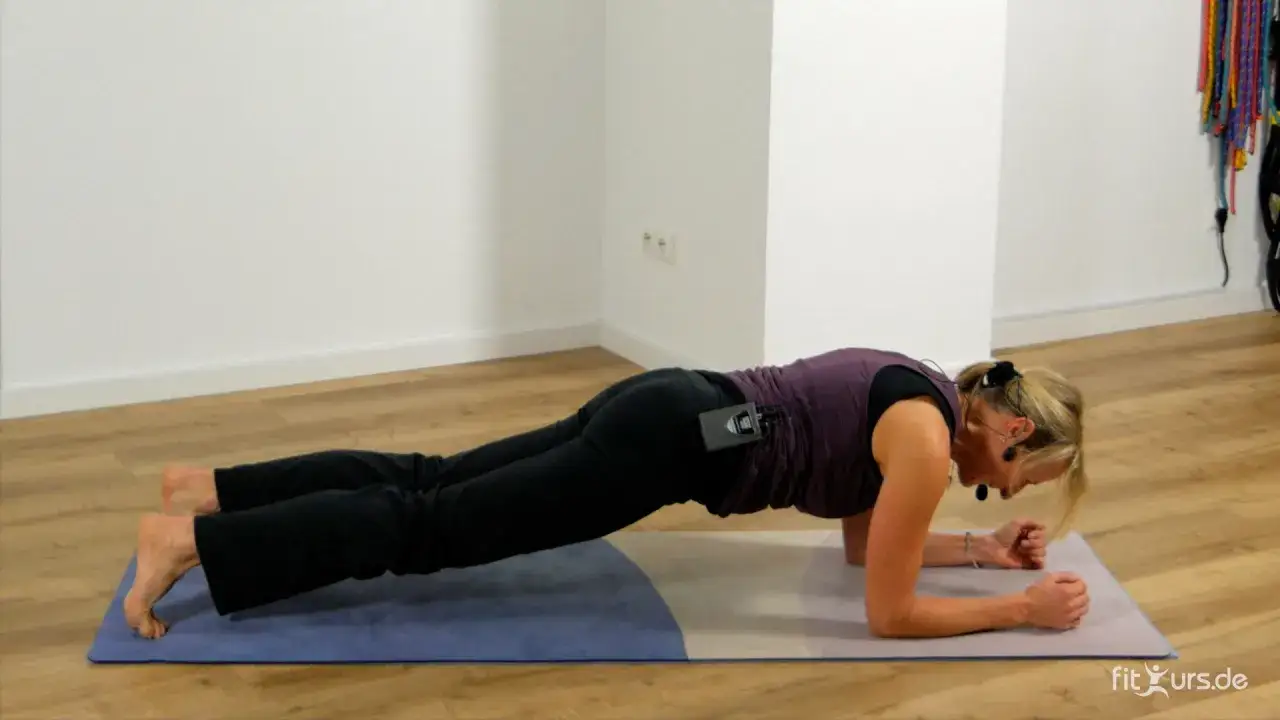Frau in Unterarmstützposition, eine von vielen Plank Varianten, trainiert ihren Körper auf einer Matte.