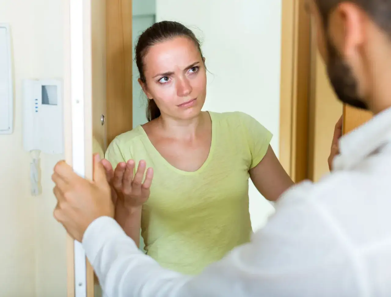 Une femme exaspérée fait face à un homme à sa porte, signe d'un trouble anormal de voisinage.