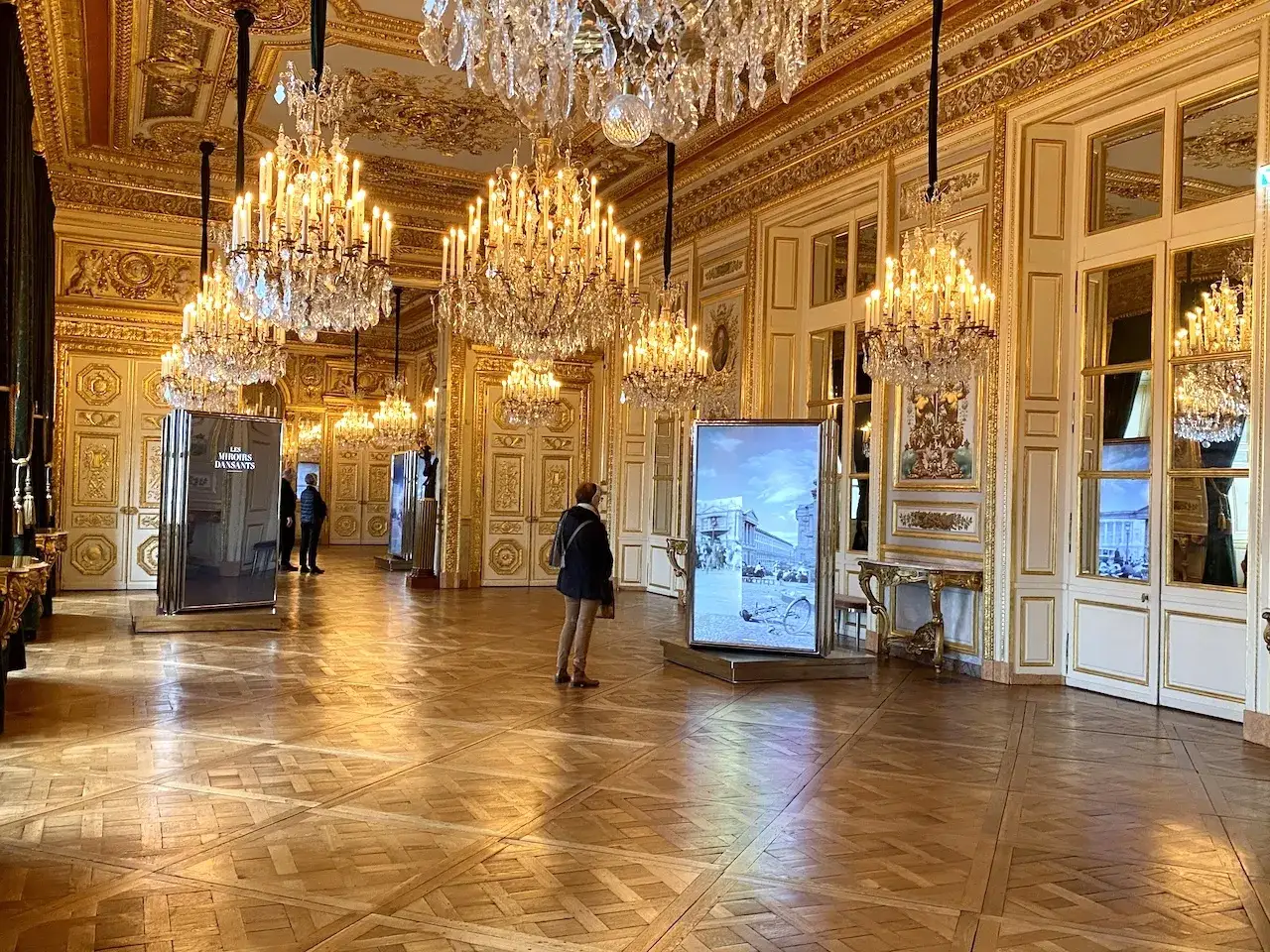 Intérieur doré du **hôtel de la Marine**, avec des lustres étincelants, des panneaux muraux ornés et des expositions.