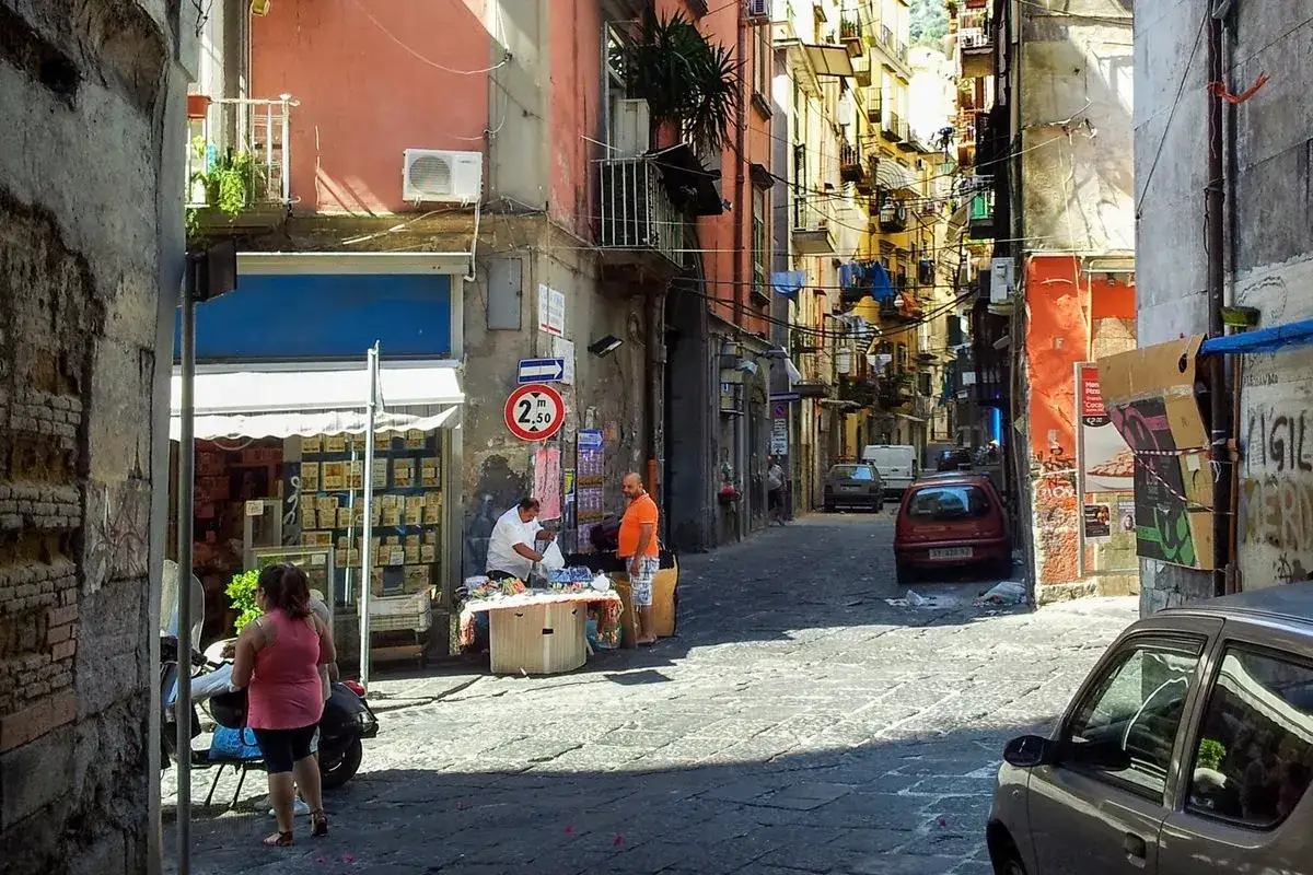 Vicoli napoletani pieni di vita, con venditori ambulanti e palazzi colorati.