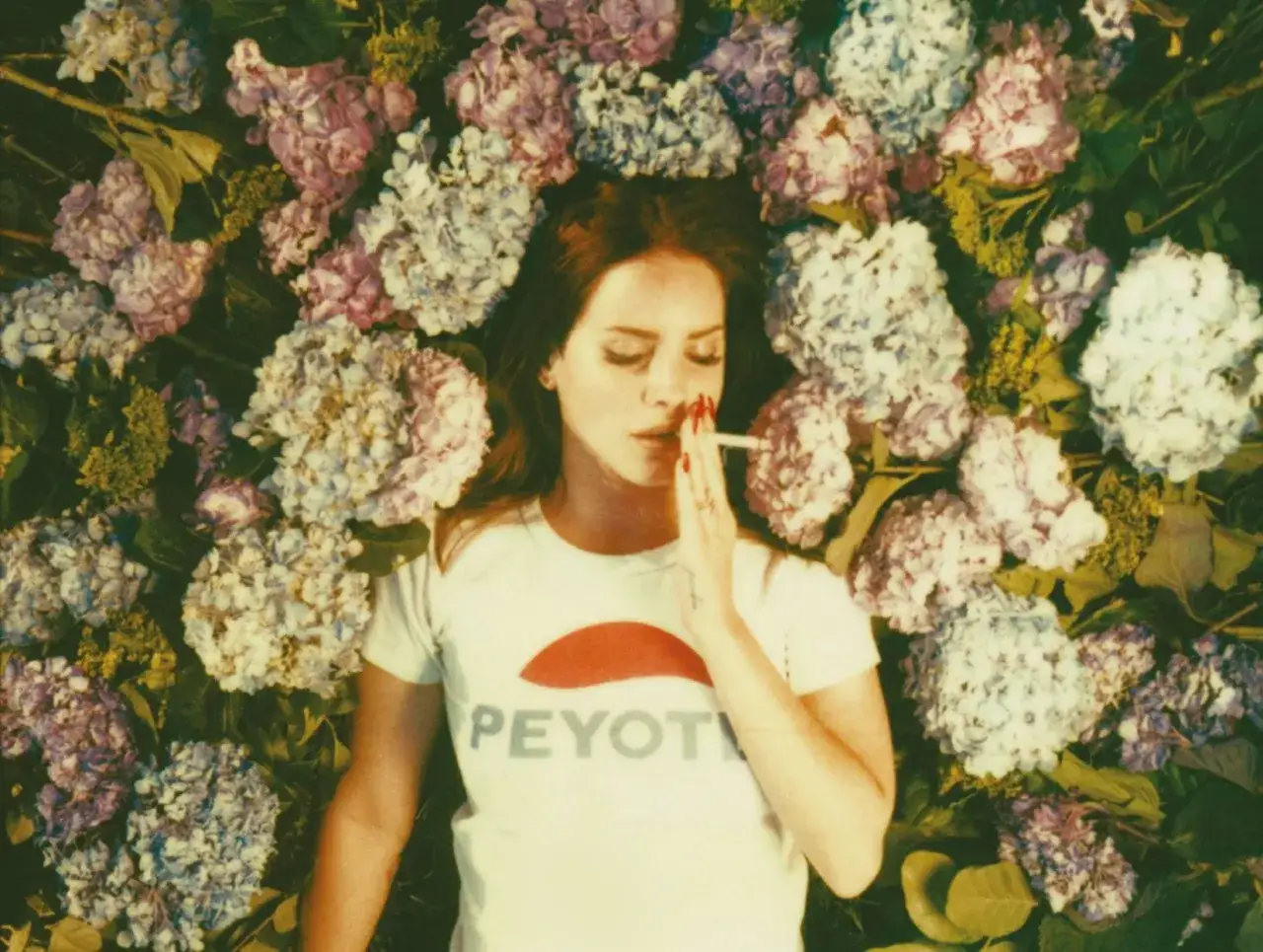 Lana Del Rey, otoczona kwiatami, z papierosem w dłoni. Okładka albumu