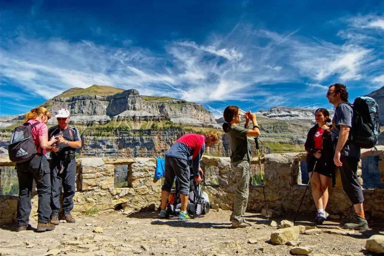 Grupo de excursionistas en la senda de los cazadores, disfrutando de un paisaje monta&ntilde;oso bajo un cielo azul con nubes.