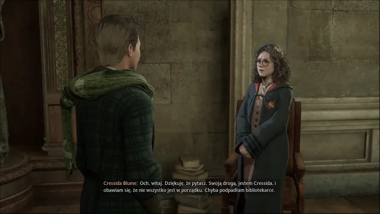 Postać z gry Hogwarts Legacy, z polskim dubbingiem, rozmawia z inną postacią w szacie.