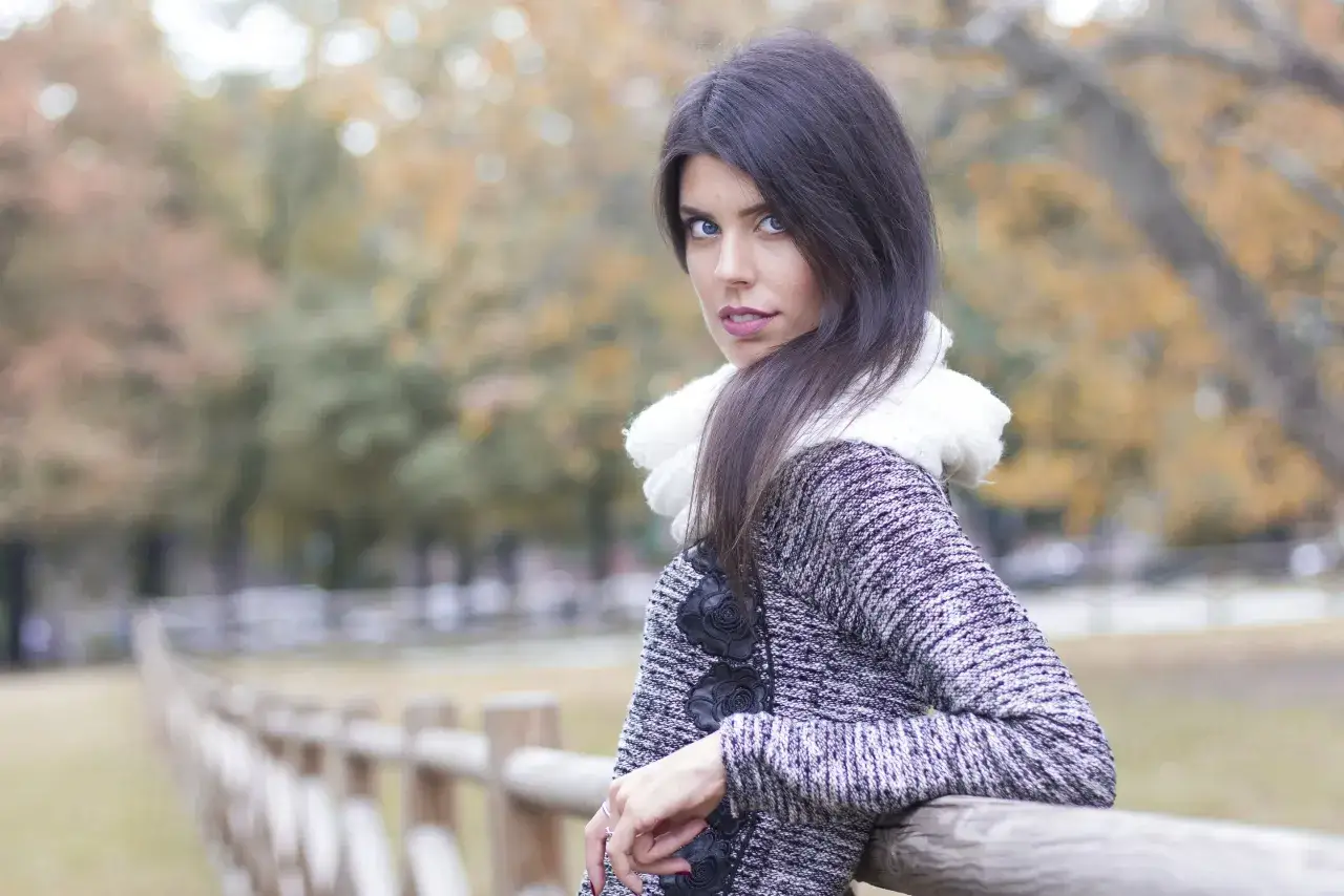 Ritratto di una giovane donna con occhi azzurri penetranti, indossa una sciarpa bianca e un cappotto grigio. #portrait