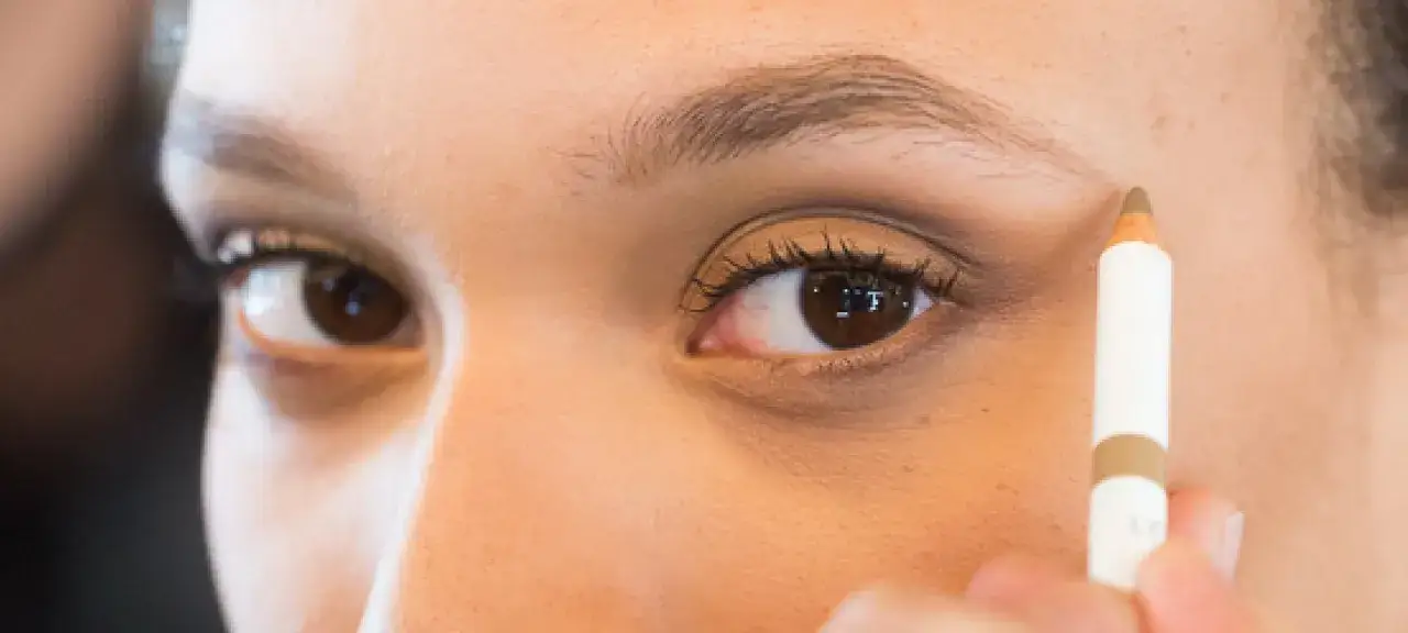 Detalle de ojo con l&aacute;piz de maquillaje, perfilando la ceja. Se busca un efecto de decolorar cejas para un look natural.