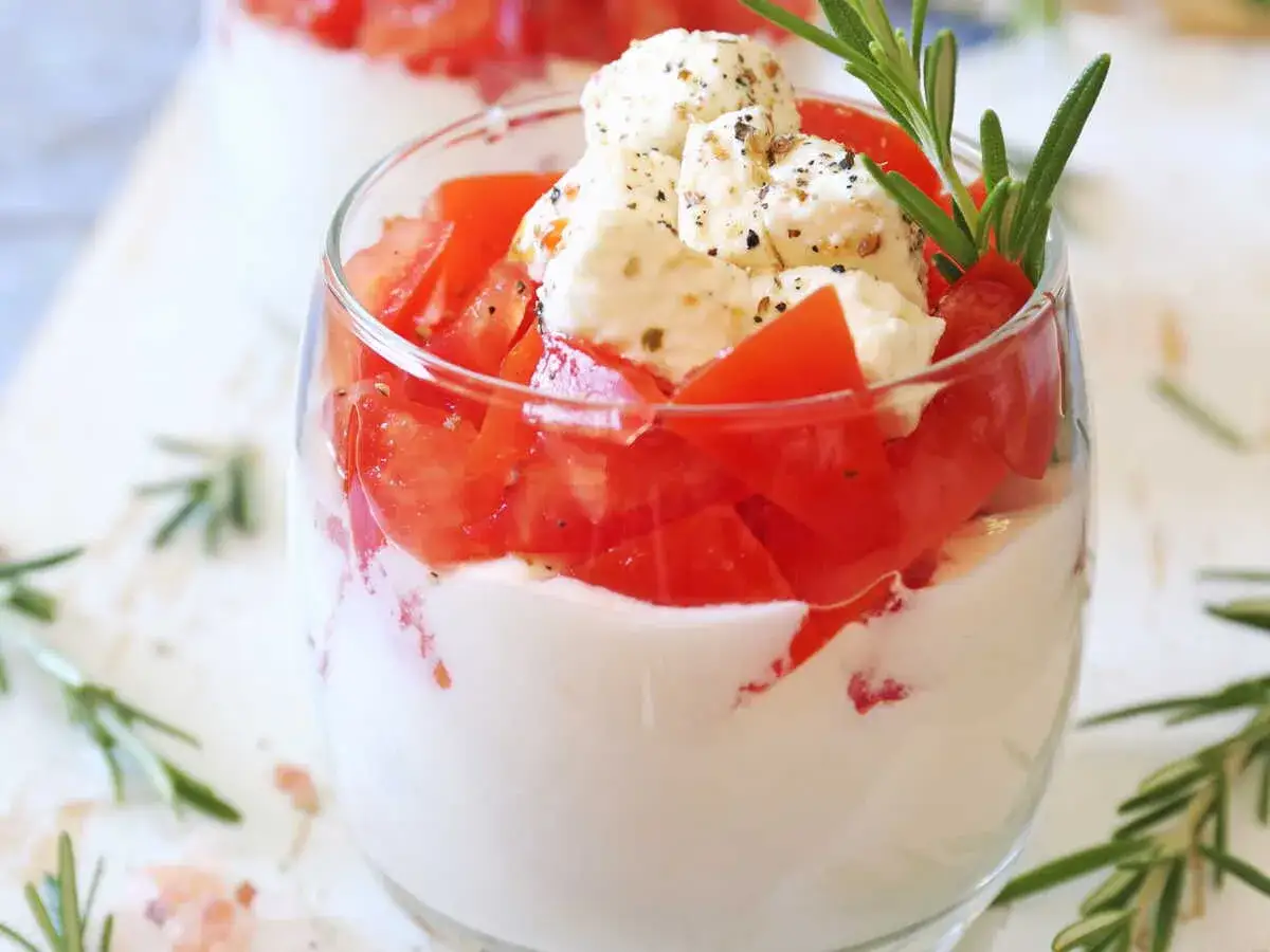 Un tiramisu salé gastronomique revisité : couches de crème onctueuse, tomates fraîches et dés de mozzarella assaisonnés, garni de romarin.