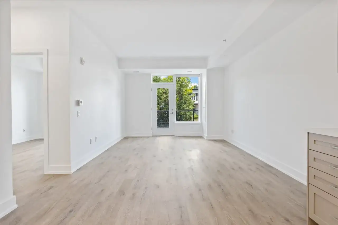 Sal&oacute;n luminoso con suelo de madera clara y puerta acristalada que da a un balc&oacute;n con &aacute;rboles. Ideal para vender piso heredado antes de 5 a&ntilde;os.