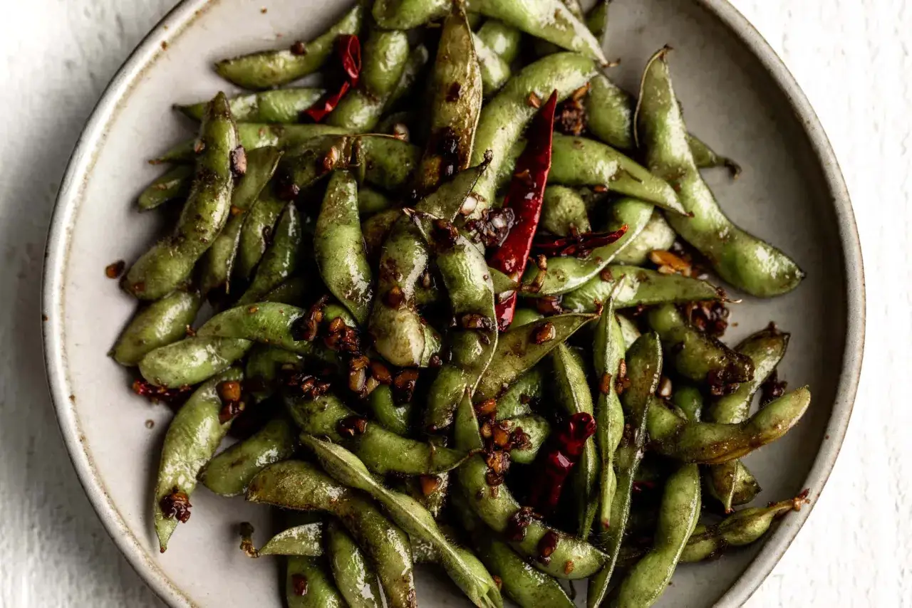 Miseczka pełna zielonej fasolki edamame, polanej pikantnym sosem z chili i czosnkiem.