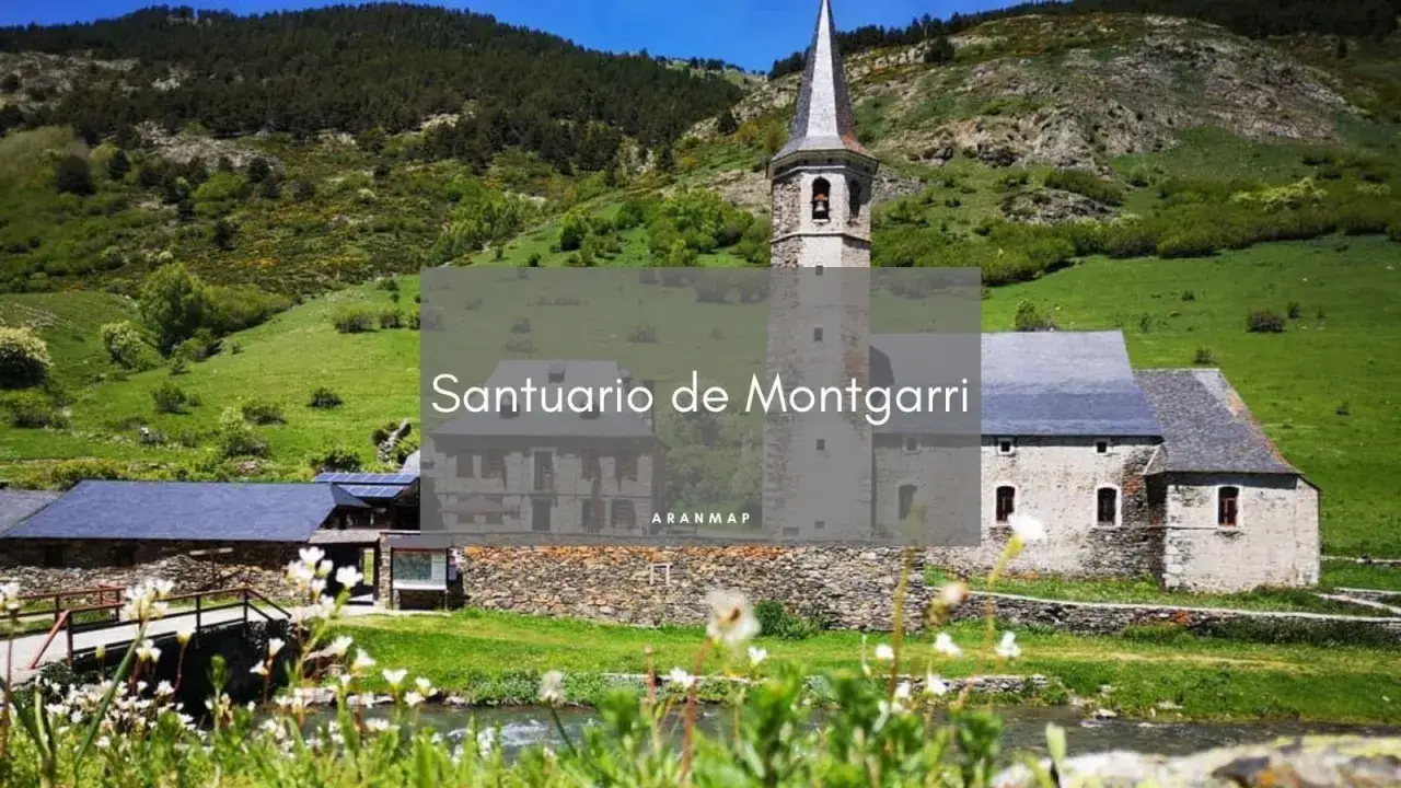 El Santuari de Montgarri, un edificio de piedra con campanario, se alza en un valle verde con monta&ntilde;as boscosas al fondo.