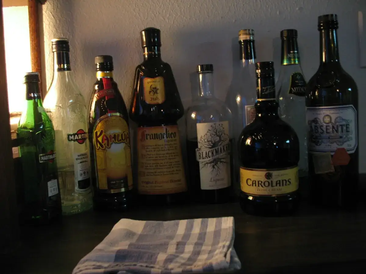 Rząd butelek z r&oacute;żnymi likierami: zielony Martini, Kahl&uacute;a, Frangelico, Blackmaker, Carolans Irish Cream, Absente. Co to likier? To słodki alkohol.