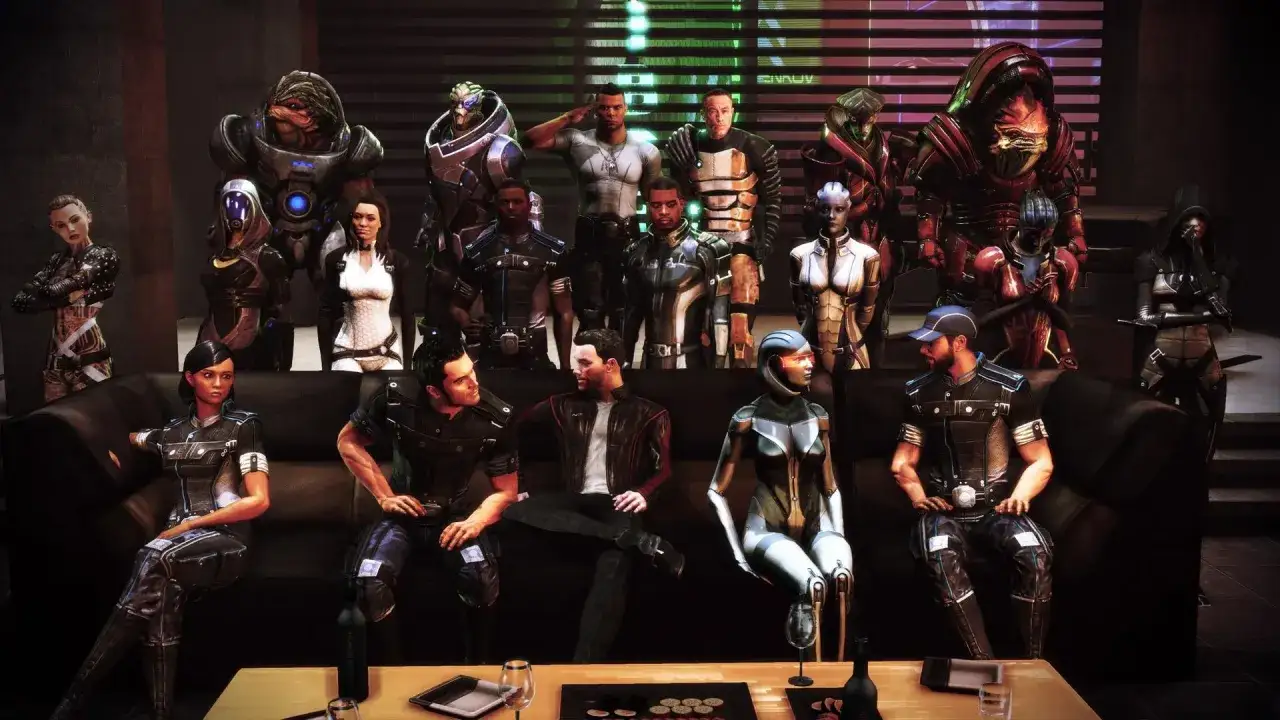 Postacie z serialu Mass Effect w futurystycznym wnętrzu. Na kanapie siedzą ludzie i asari, za nimi stoją turianie, krogani i inni.