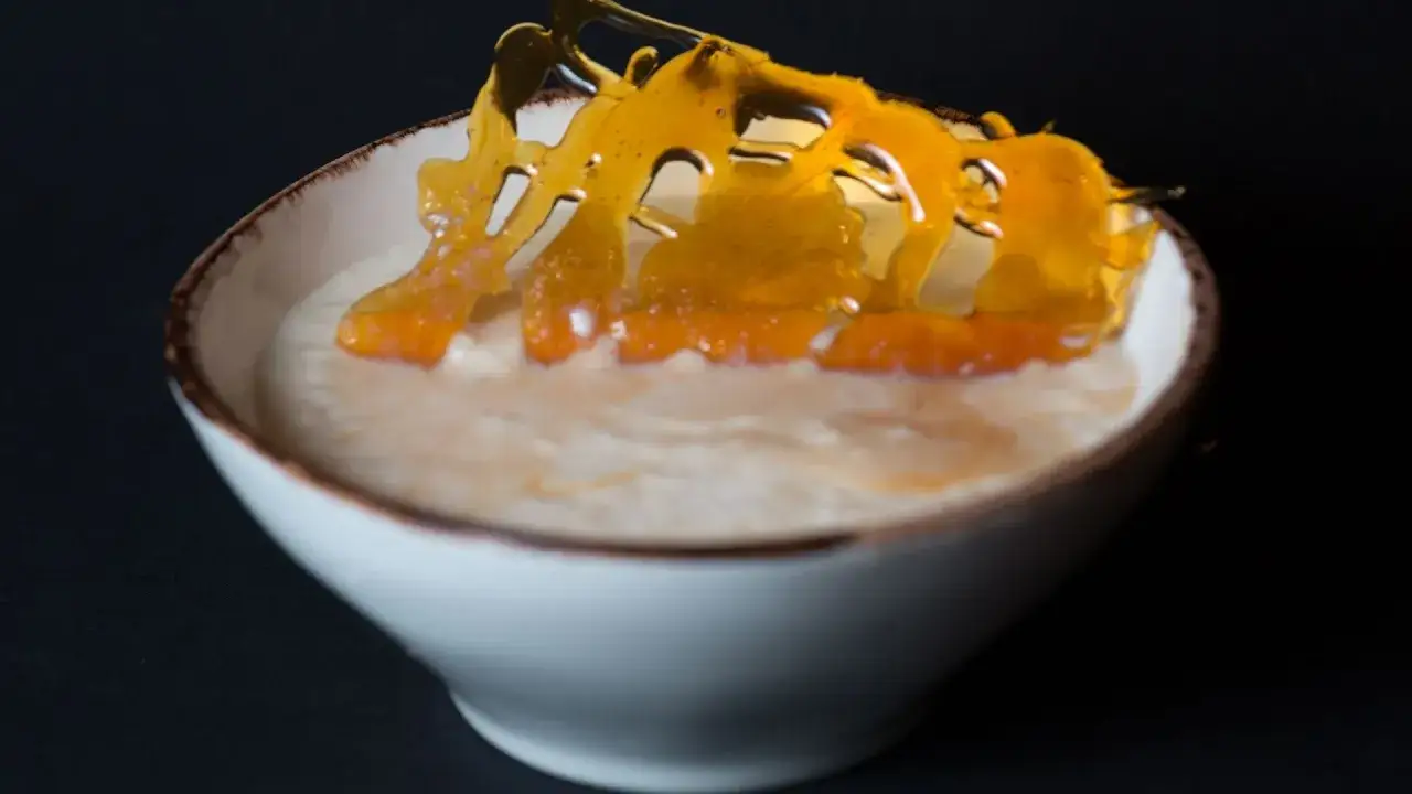 Un bol de riz au lait cr&eacute;meux, garni d'une d&eacute;coration en caramel ambr&eacute; et de morceaux d'orange confite.