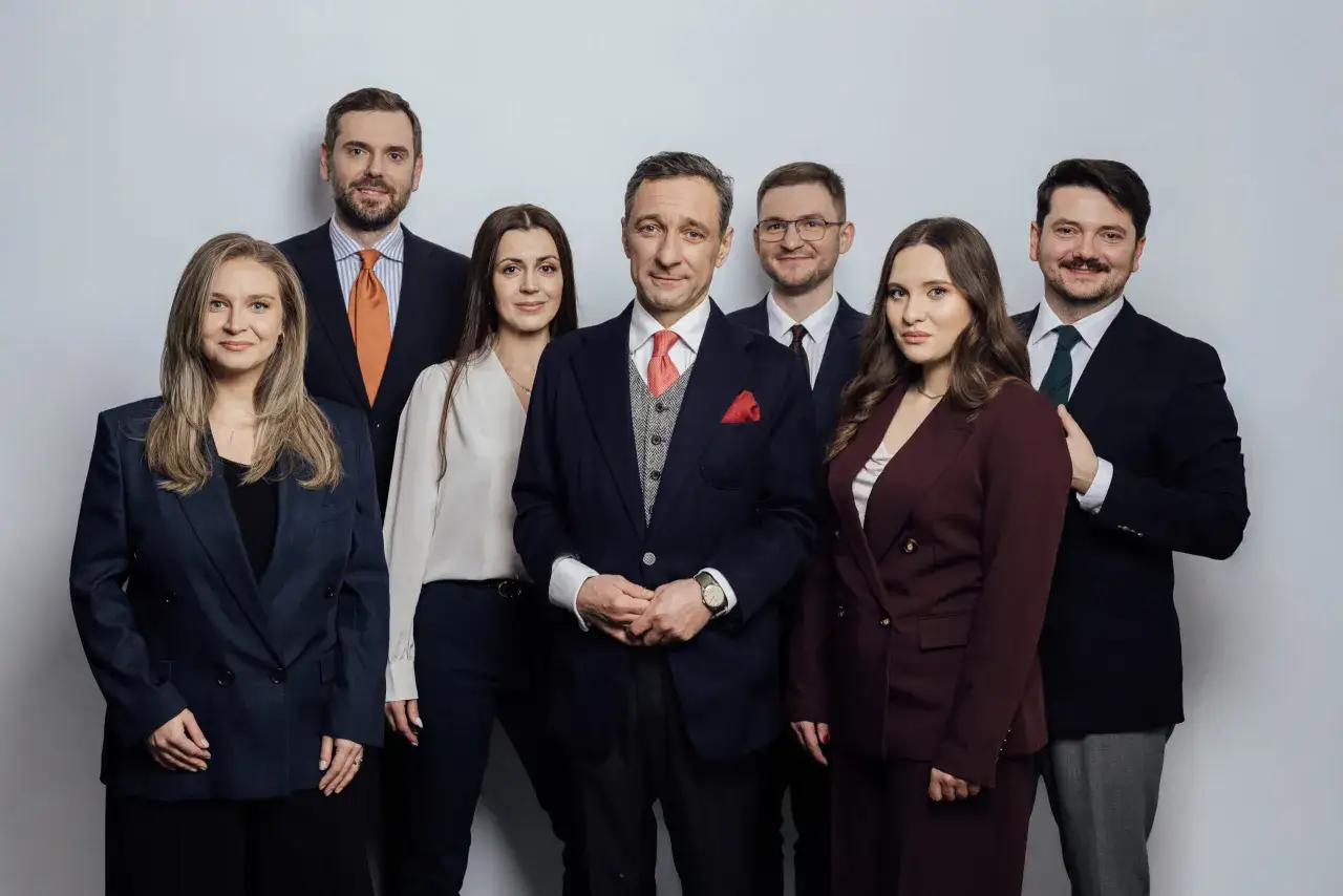 Grupa prawników i radców prawnych w garniturach i eleganckich strojach pozuje do zdjęcia.