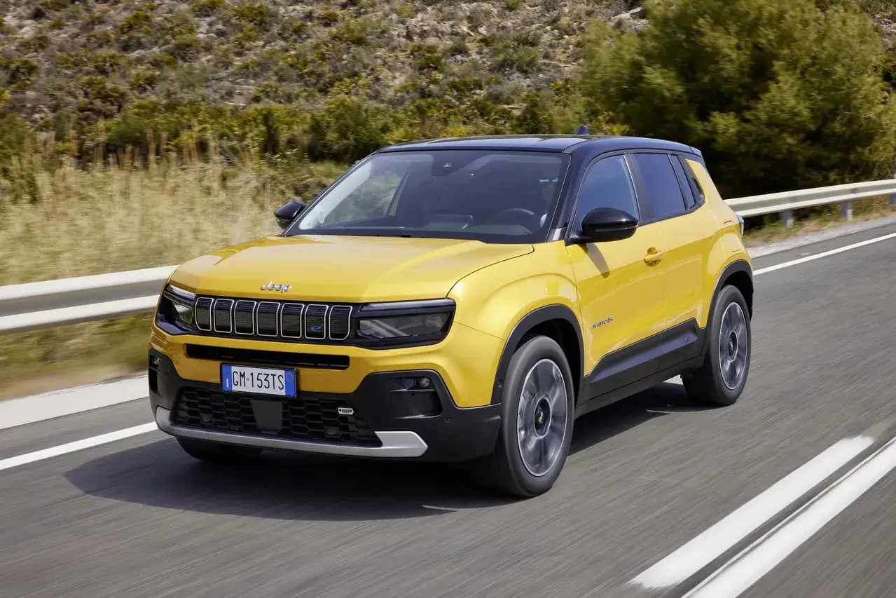 Le Jeep Avenger jaune, le plus petit SUV de la marque, roule sur une route de campagne ensoleillée.