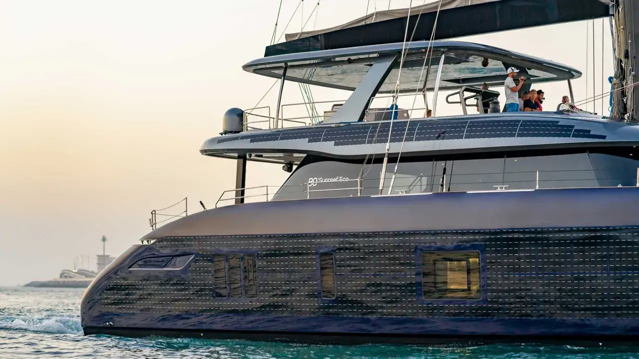 Un catamaran électrique moderne navigue sur l'eau, avec des panneaux solaires intégrés sur le toit.
