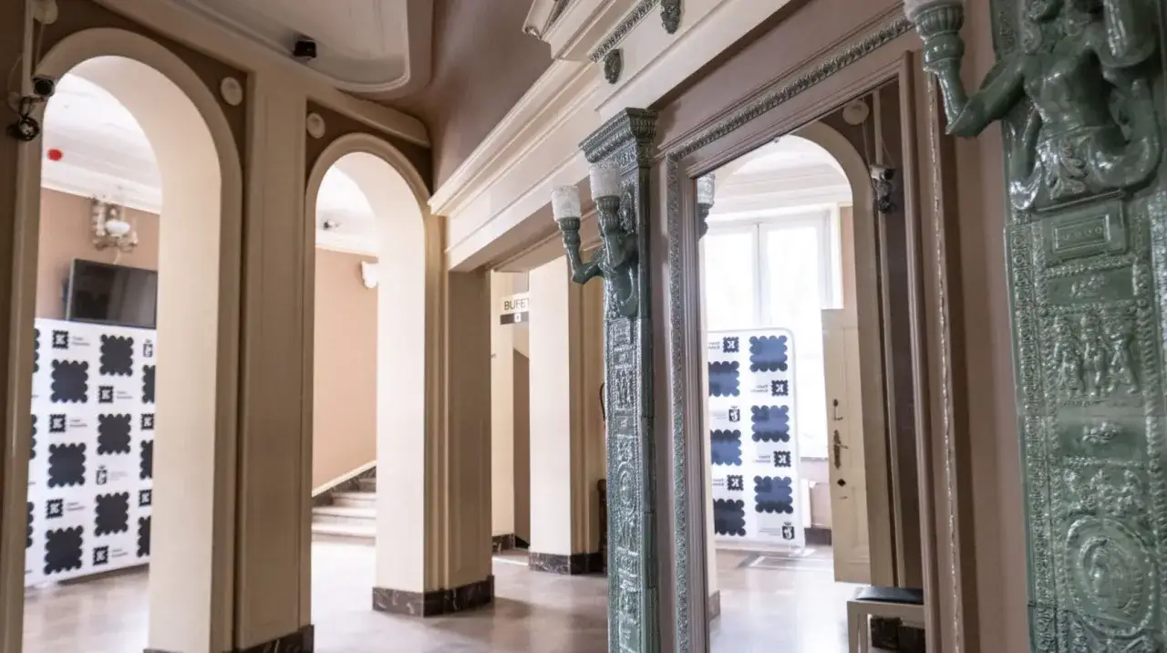 Wnętrze teatru komedia Wrocław. Eleganckie arkady, zabytkowy piec i banery z logo teatru.