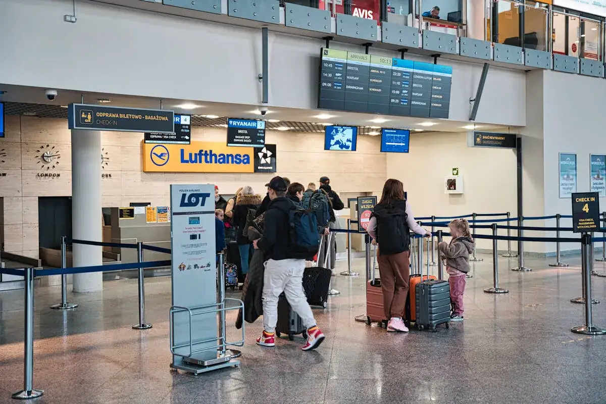 Kolejka do odprawy na lotnisku Bydgoszcz. W tle tablice lotów i logo Lufthansy.