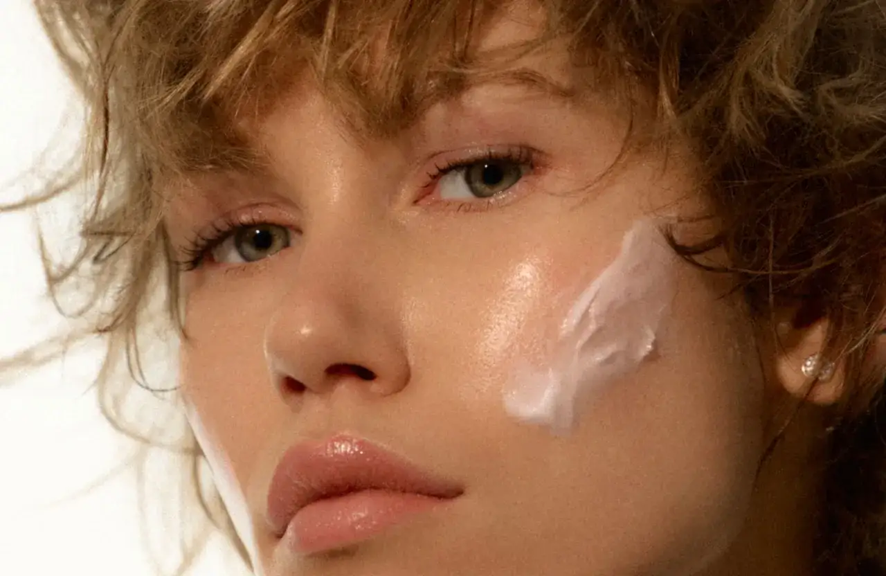 Visage d'une femme avec une touche de cr&egrave;me sur la joue, &eacute;voquant les soins pour les probl&egrave;mes de peau et la m&eacute;nopause.