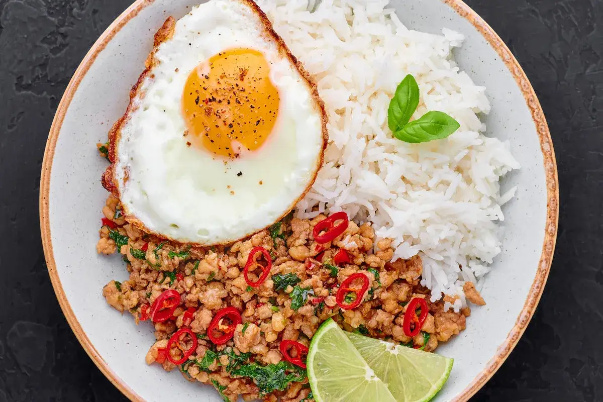 Pad tha&iuml; au porc, riz blanc, &oelig;uf au plat, piments rouges et quartiers de citron vert. Un plat savoureux et color&eacute;.