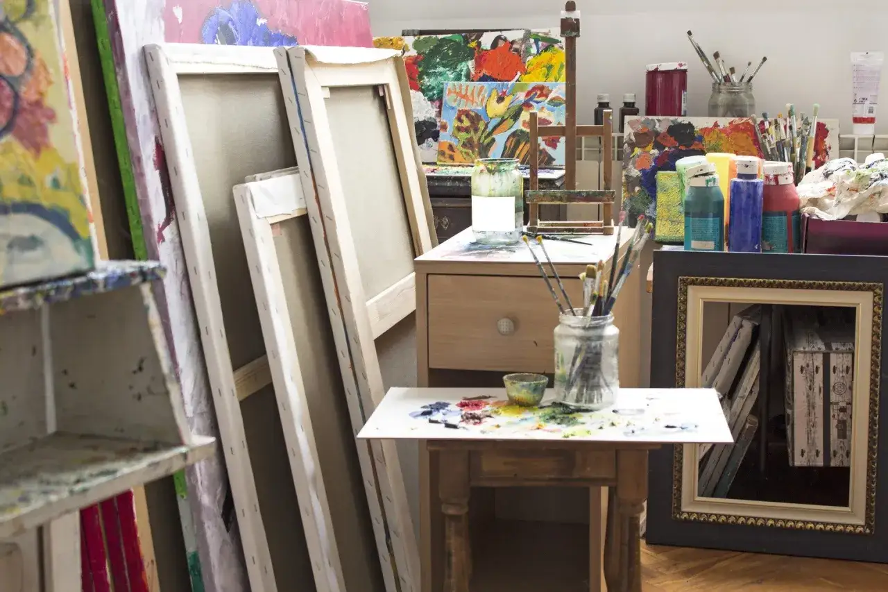 Artystyczna pracownia pełna płócien i farb, inspirująca do wyboru kreatywnych kierunków studiów.