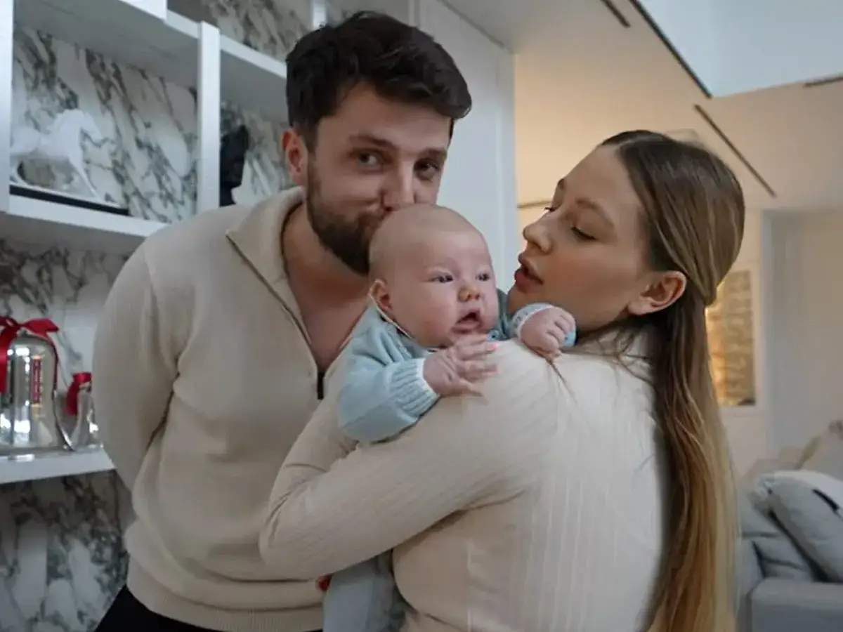 Rodzice czule tulą synka. Ojciec całuje go w czoło, a mama patrzy na niego z miłością.