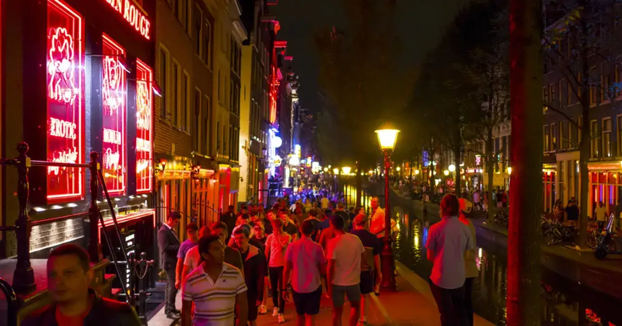 Nocna, czerwona ulica Amsterdamu, pełna neonów i ludzi.