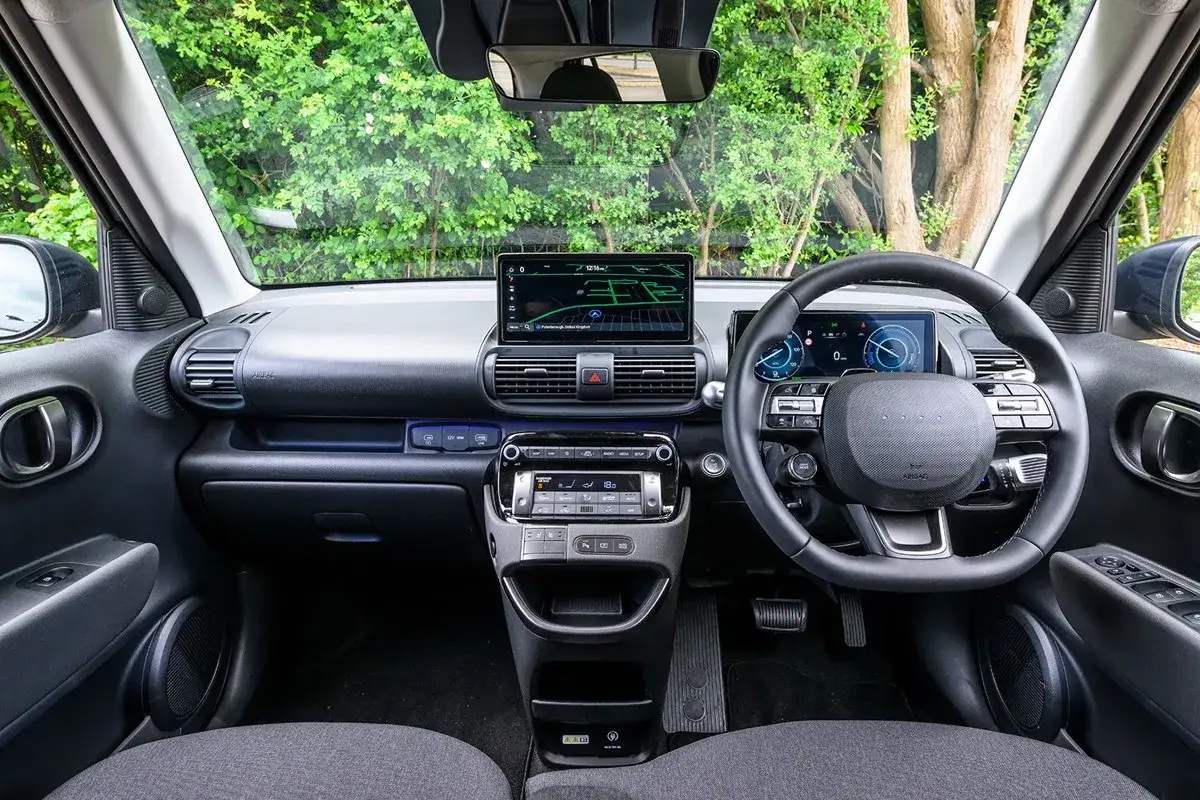 Wnętrze Hyundai Kona, z ekranem nawigacji i cyfrowymi zegarami. Sprawdź hyundai inster cena i odkryj nowoczesne rozwiązania.
