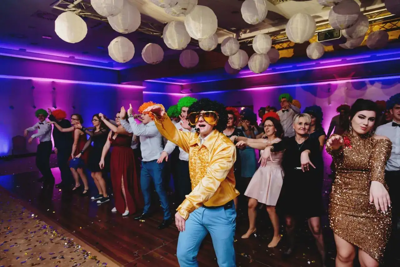 Szalone wesele w Polsce! Goście w kolorowych perukach i błyszczących strojach tańczą pod lampionami.