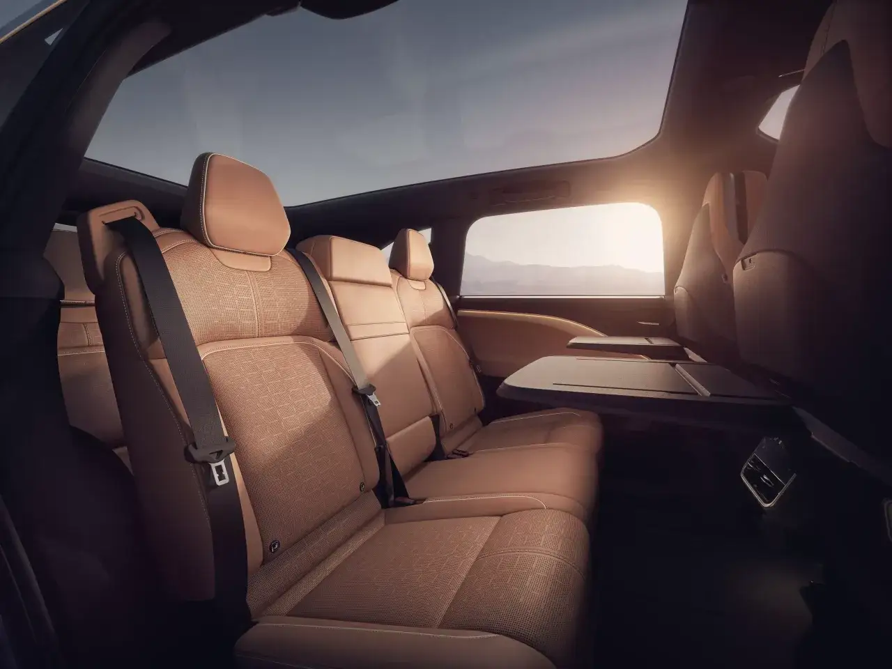 Luxuriöse Ledersitze im Auto, die ein Gefühl von **lucid gravity** vermitteln. Das Panoramadach lässt die Sonne herein, während die ausklappbaren Tische für Komfort sorgen.