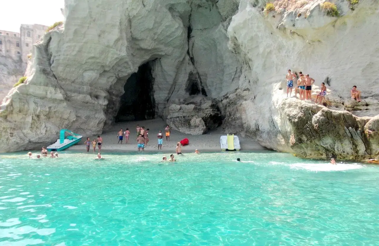 Bambini e adulti si divertono nella grotta del Palombaro, tra scogli e acque cristalline.