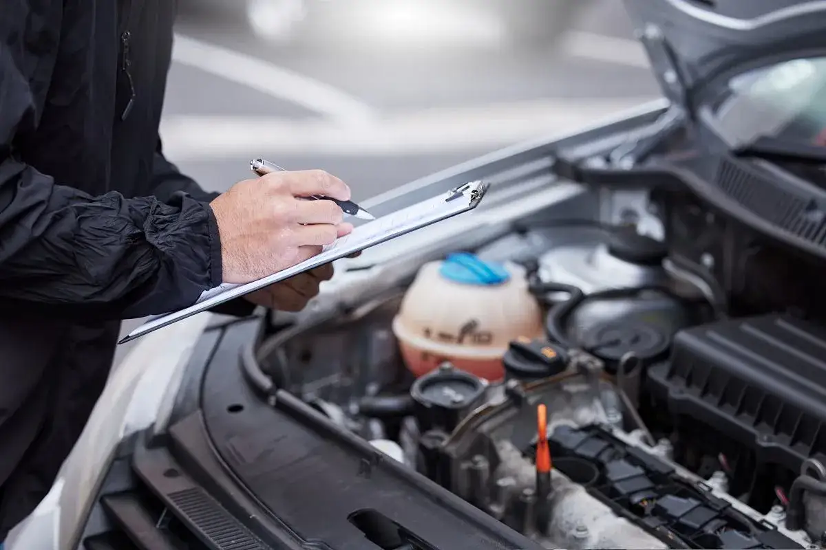 Mechanik spisuje listę kontrolną, zastanawiając się, ile kosztuje przegląd auta z gazem.