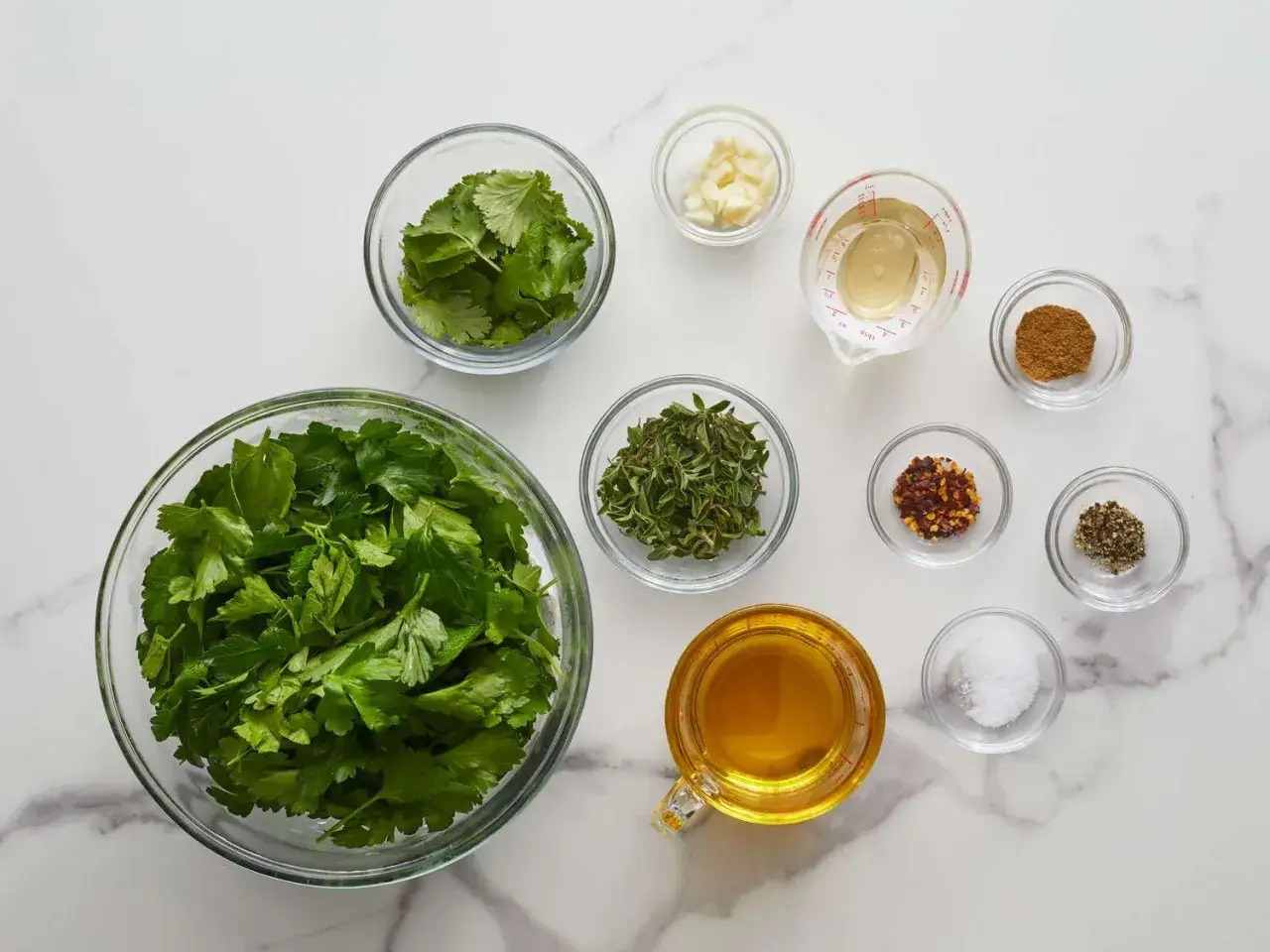 Alla ingredienser f&ouml;r ett fantastiskt chimichurri recept: f&auml;rska &ouml;rter, vitl&ouml;k, vin&auml;ger, olja och kryddor.