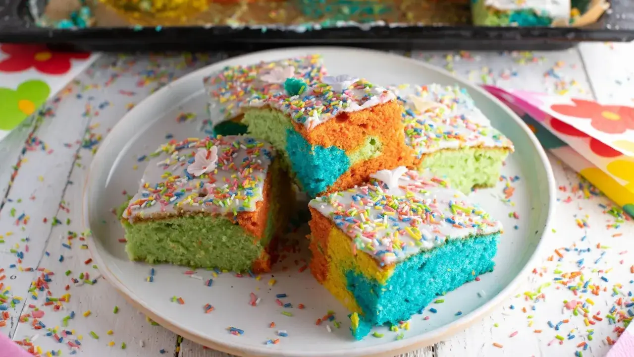 Bunte Kuchenstücke mit Zuckerguss und Streuseln, die an ein Papageienkuchen Rezept erinnern.