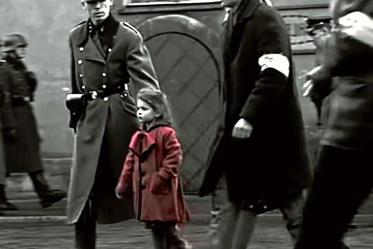 Dziewczynka w czerwonym płaszczu idzie wśród żołnierzy. Scena z filmu 