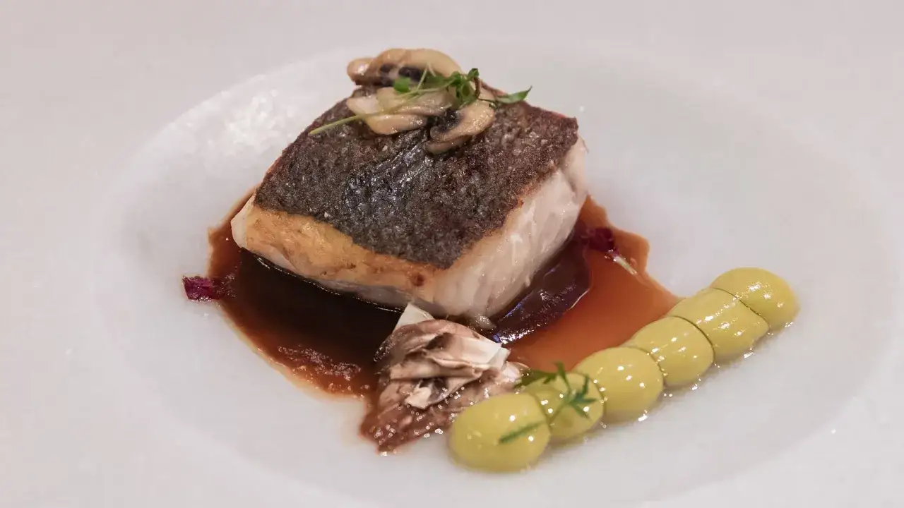 Delicioso filete de lubina a baja temperatura, crujiente por fuera, jugoso por dentro, con champiñones y una guarnición de puré verde.