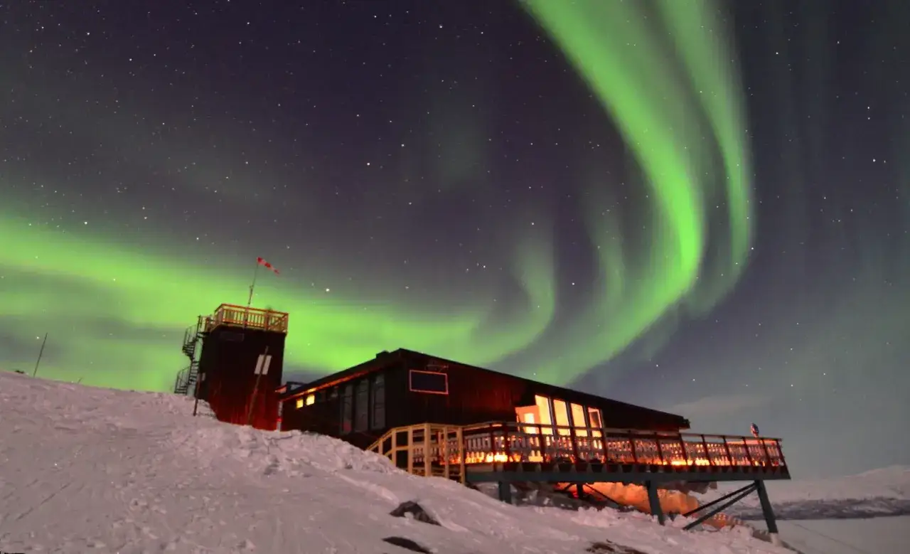 Abisko Sky Station badar i norrskenets gröna ljus. En magisk natt i Lappland.