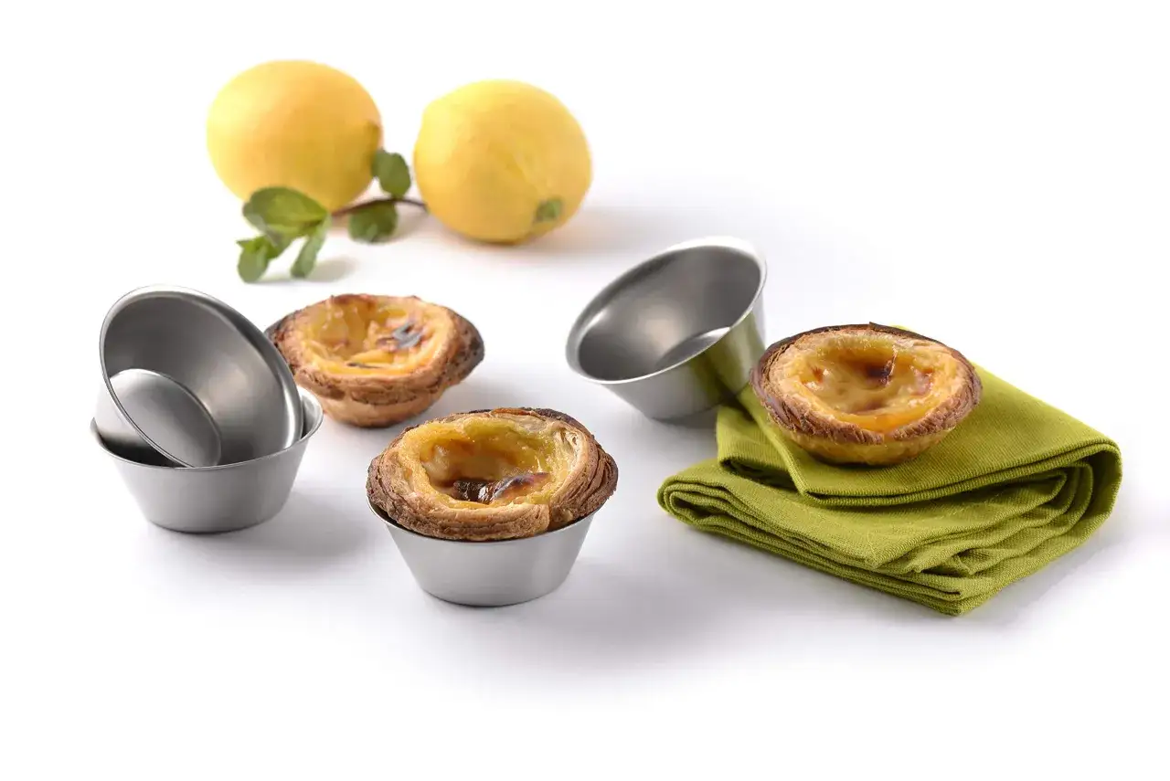 Pastel de nata portugal, deliciosos y dorados, listos para disfrutar. Dos limones y menta completan la escena.