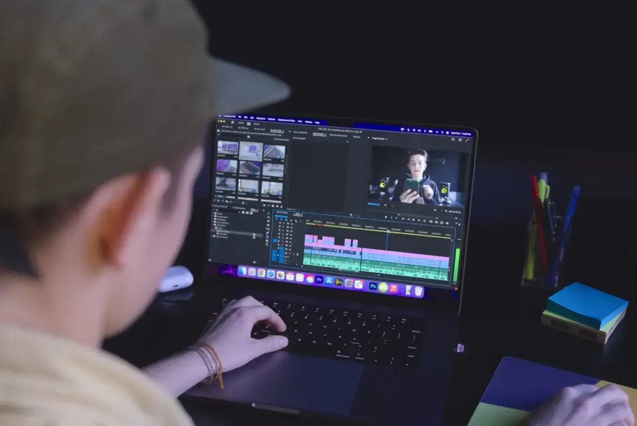 Młody mężczyzna w czapce pracuje na laptopie, edytując wideo. To świetny przykład, jaki laptop do obróbki zdjęć i filmów wybrać.