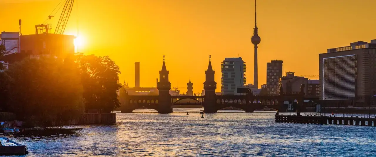Ein dramatischer Sonnenuntergang über Berlin, mit der Oberbaumbrücke und dem Fernsehturm im goldenen Licht.