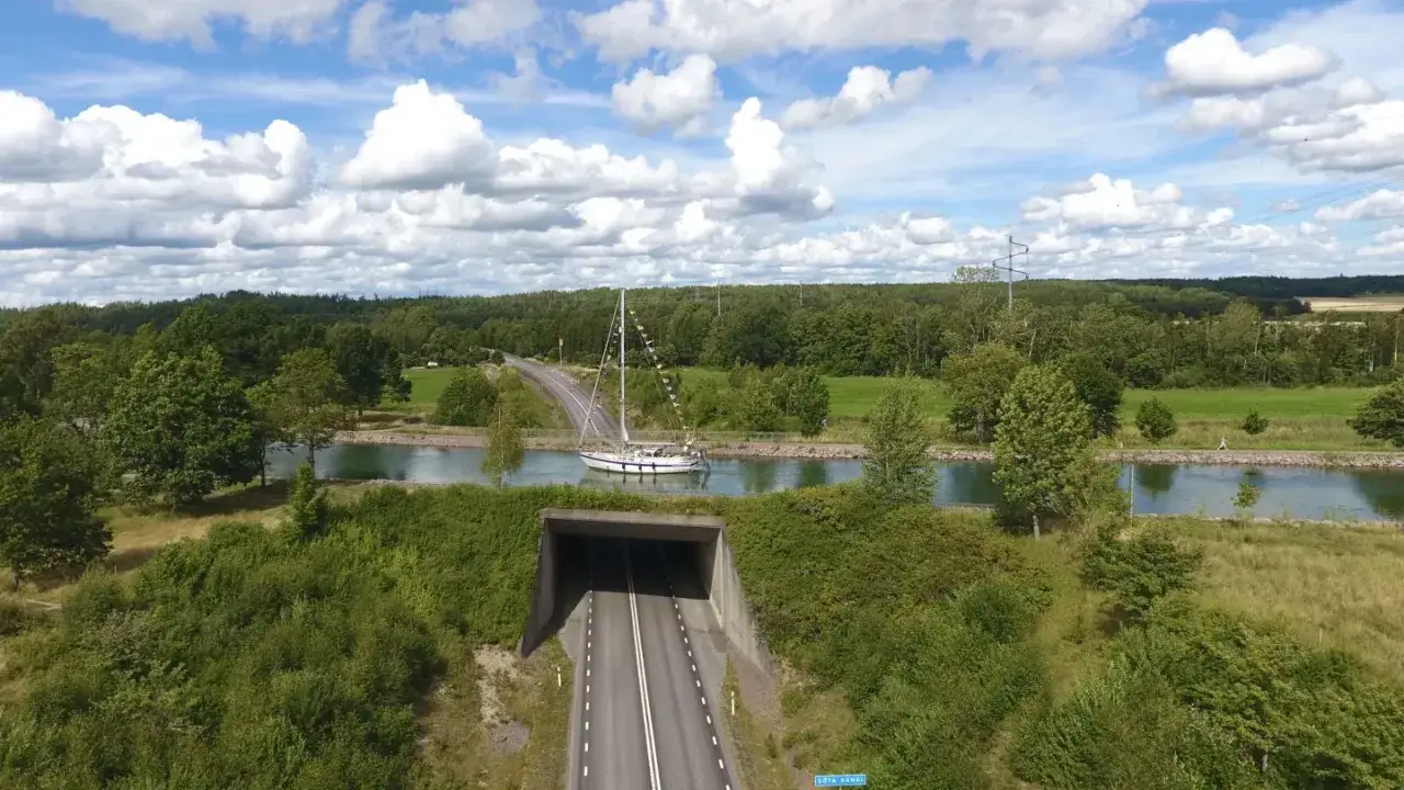 En segelbåt på en kanal, en av många akvedukter i Sverige, passerar en vägtunnel.