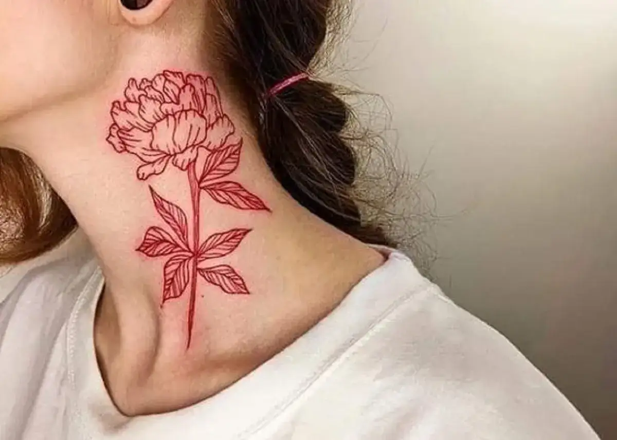 Zaczerwieniony tatuaż w kształcie piwonii na szyi. Delikatna linia podkreśla piękno kwiatu.