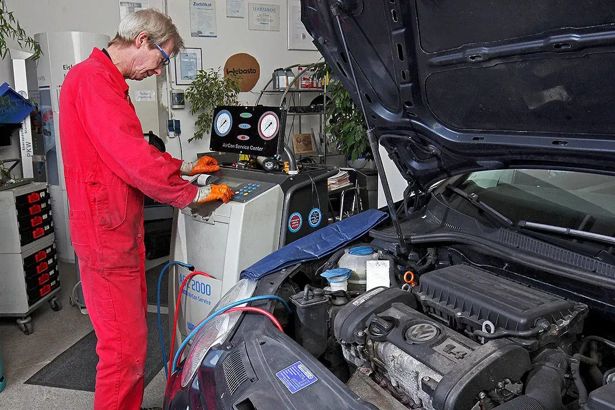Mechaniker prüft Klimaanlage. Die Kosten für die Klimaanlage reparieren sind hier im Blick.