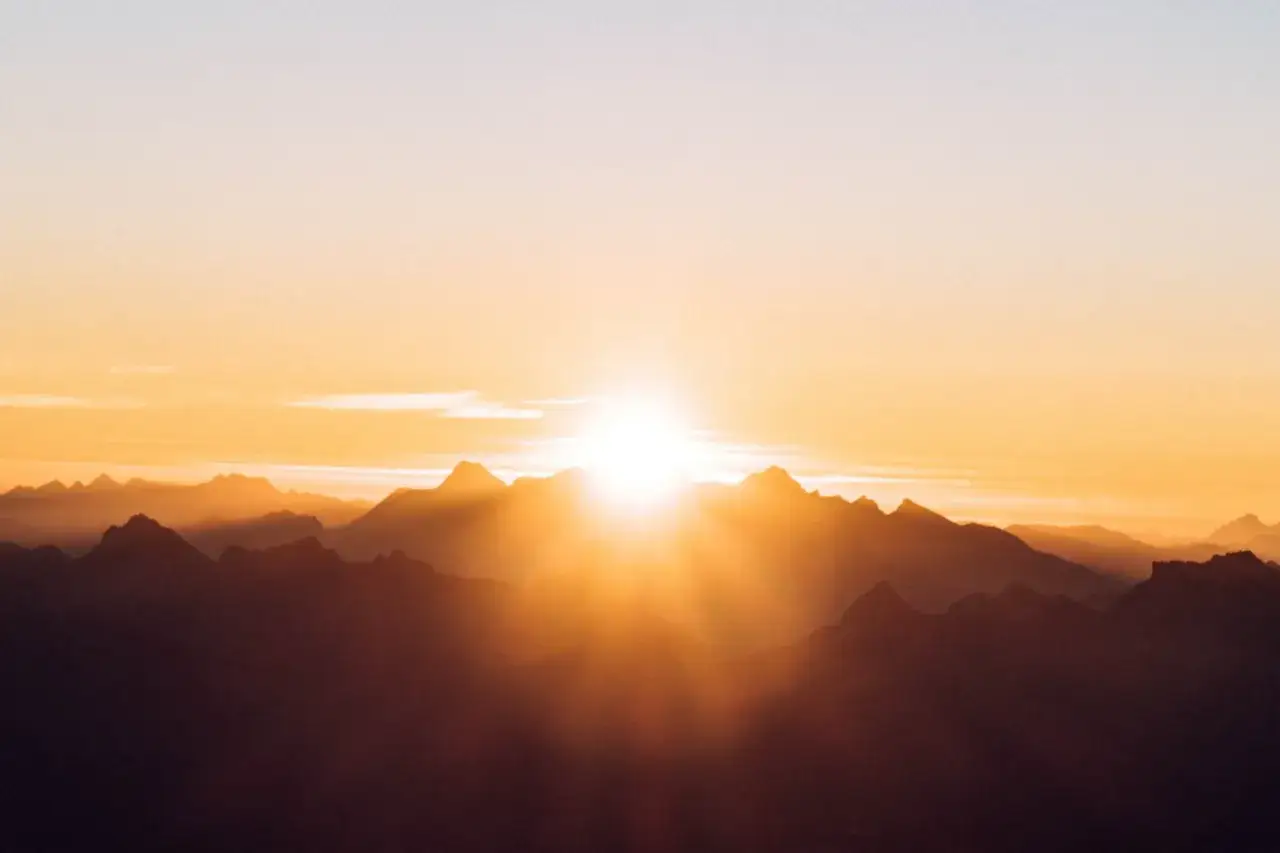 Lever soleil sur les montagnes, une scène parfaite pour apprendre comment prendre une belle photo. Les rayons dorés illuminent les sommets.