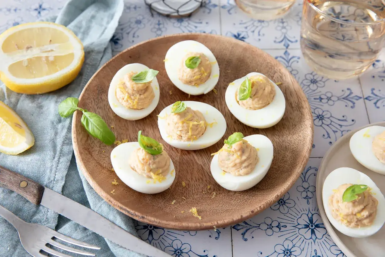 Œufs mimosa au thon, garniture crémeuse, zeste de citron et basilic frais. Une bouchée savoureuse pour l'apéritif.